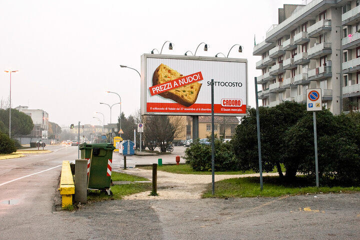 An ad, placed near a dust bin, promotes the discount on the price of food and goods of a supermarket.