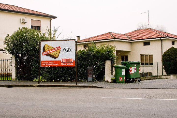 An ad, placed near a dust bin, promotes the discount on the price of food and goods of a supermarket.